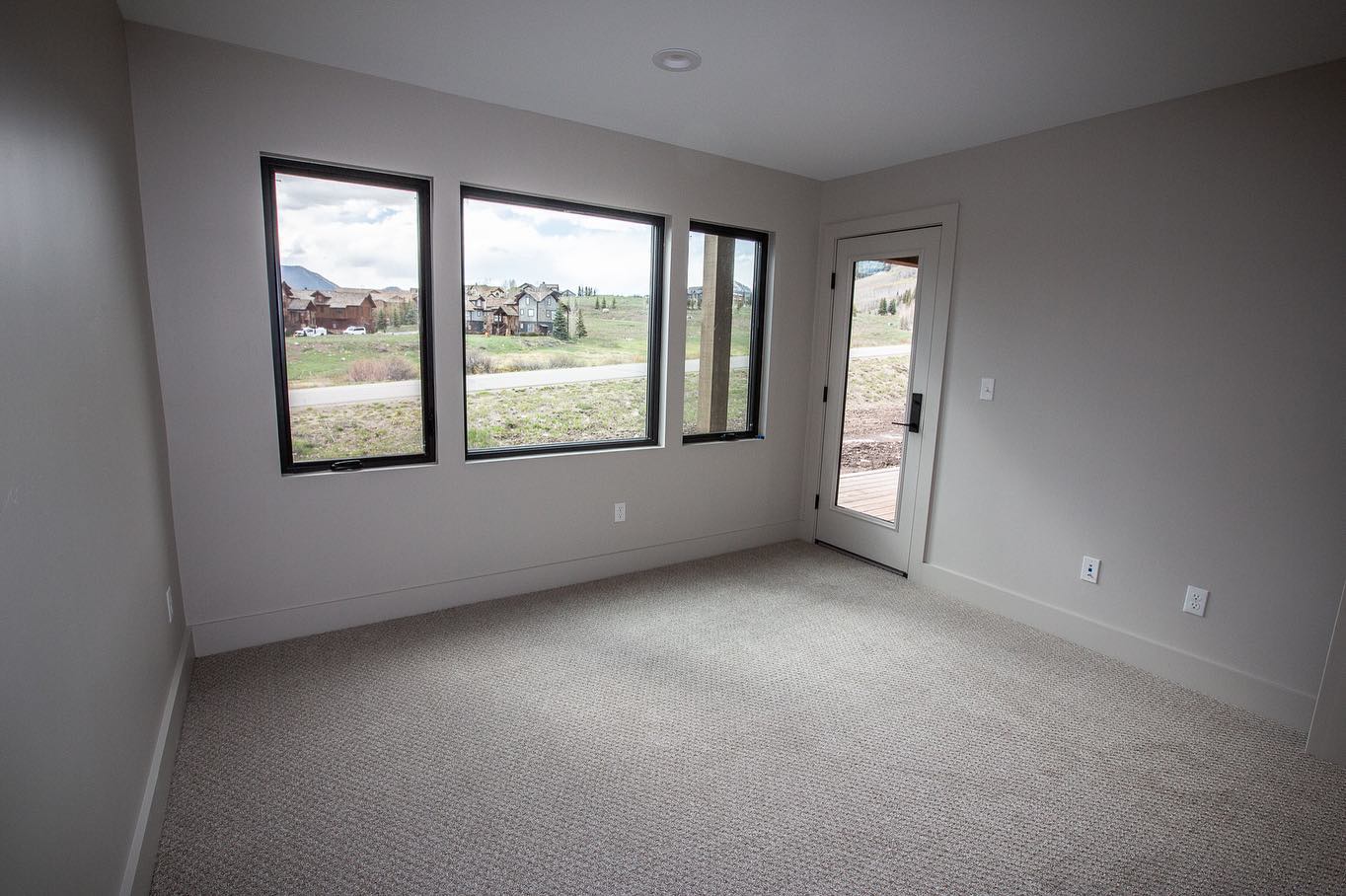 An empty room with a lot of windows and a door.