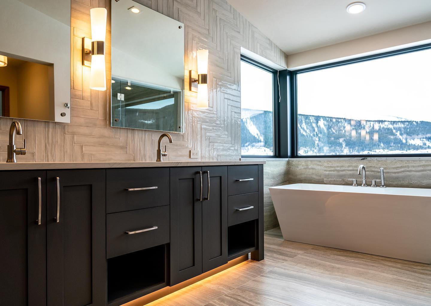 A bathroom with a tub , sink , mirror and window.