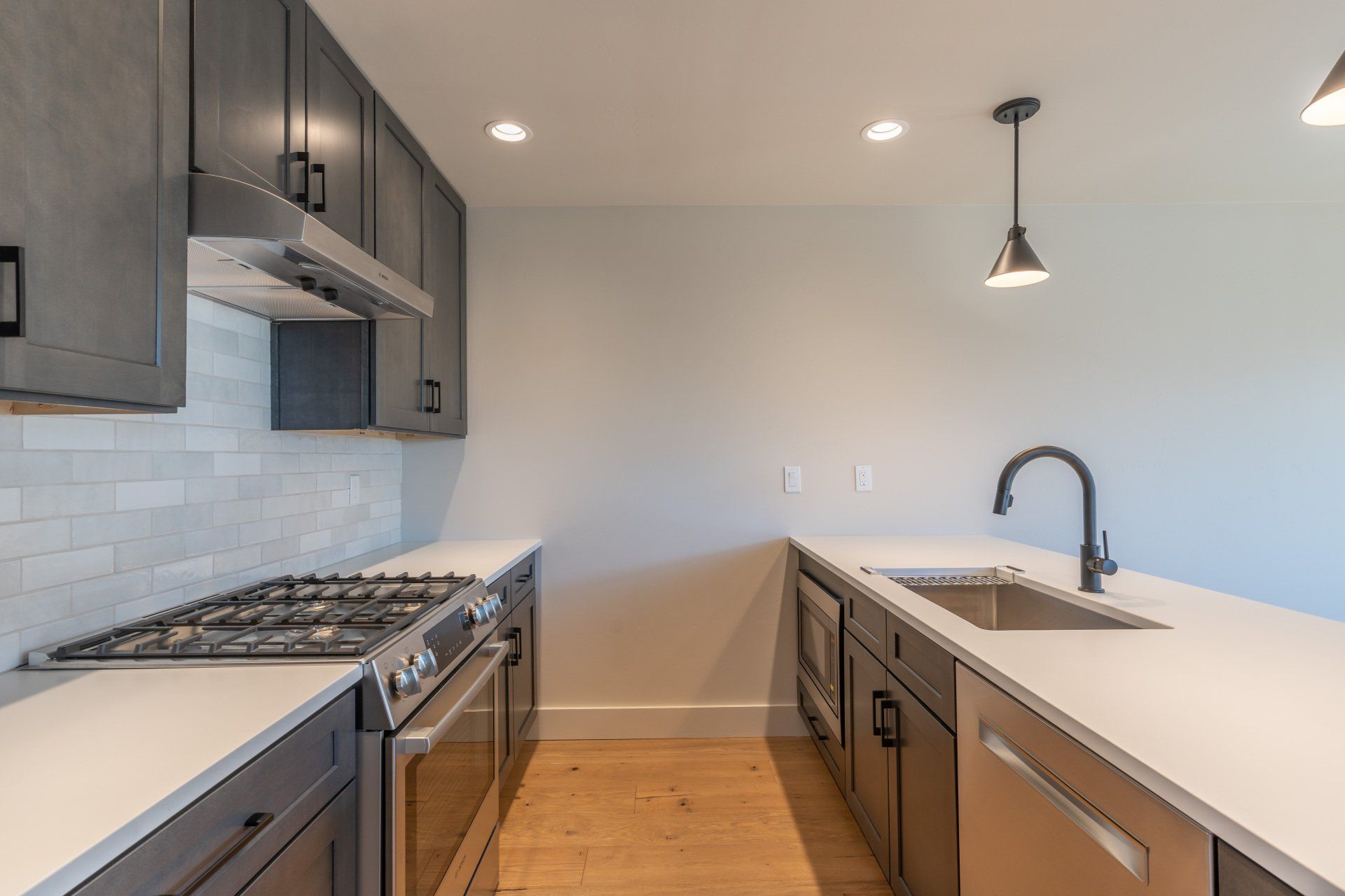 An empty kitchen with stainless steel appliances and gray cabinets