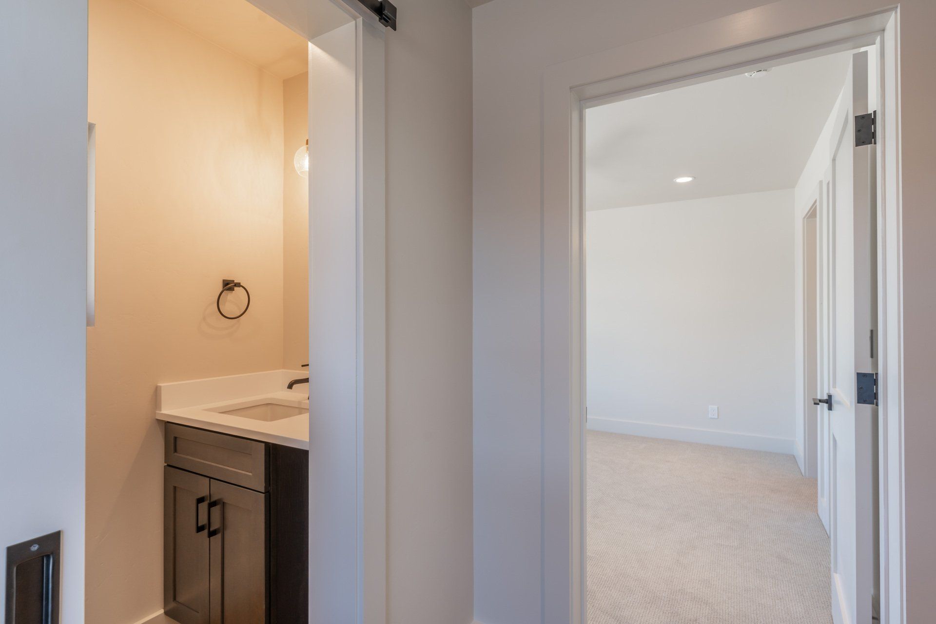 A bathroom with a sink and a door leading to a bedroom.