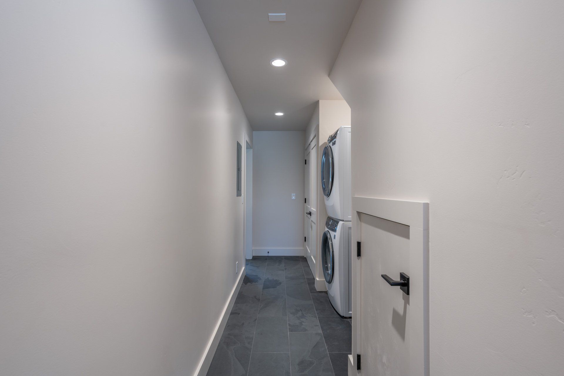 A long hallway with a washer and dryer stacked on top of each other.