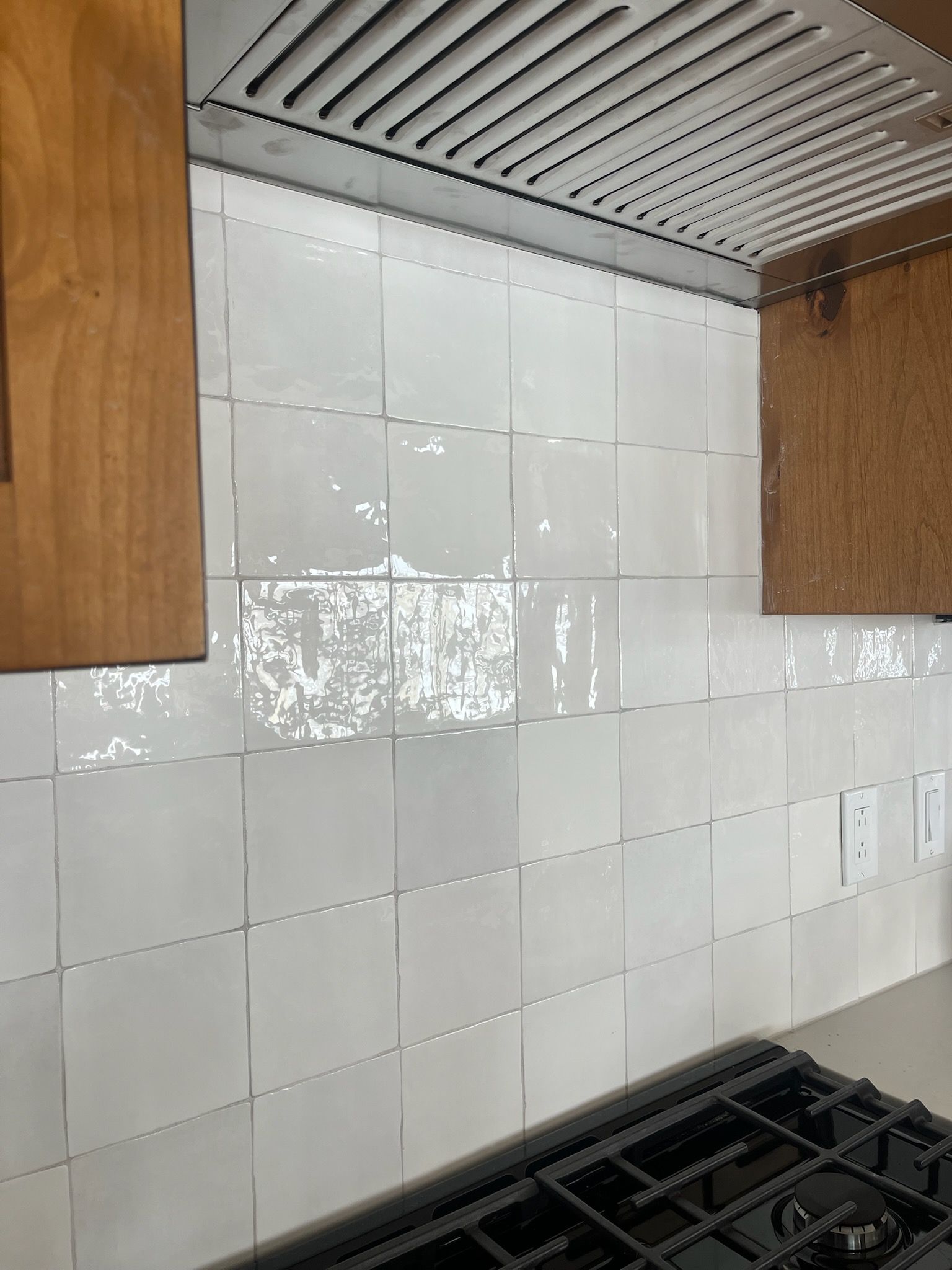 A kitchen with white tiles and a stove top oven.