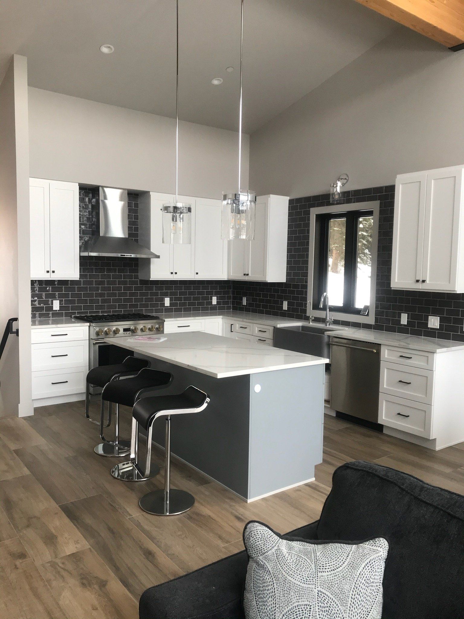 A kitchen with white cabinets , stainless steel appliances and a large island.