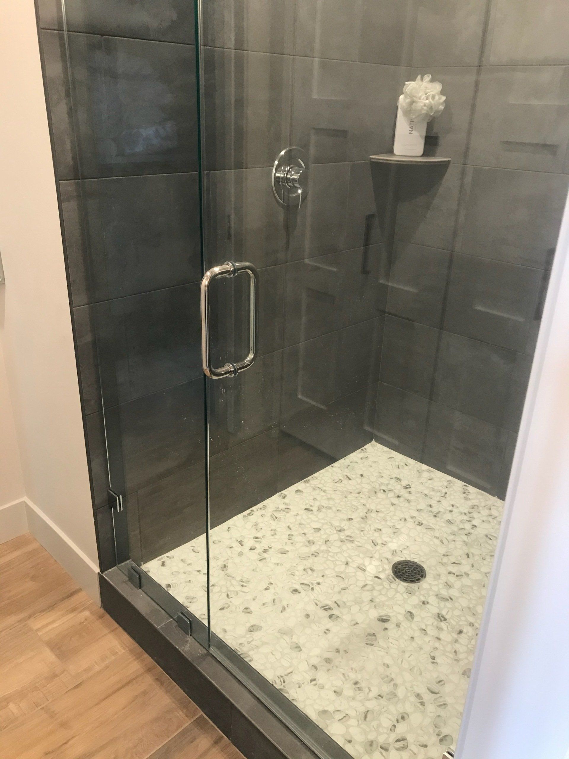 A bathroom with a walk in shower with a glass door.