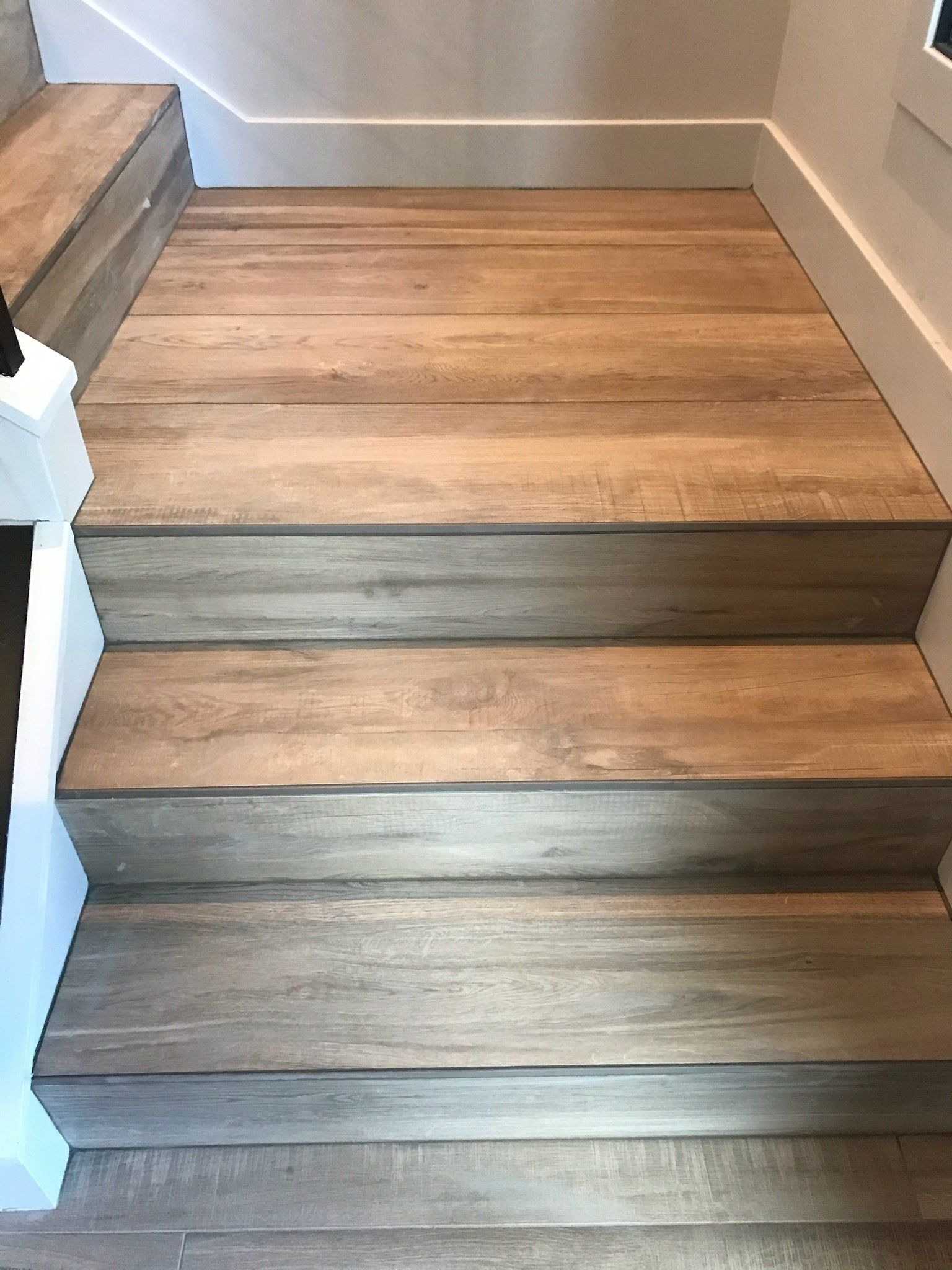 A wooden staircase with a white railing and a wooden floor.