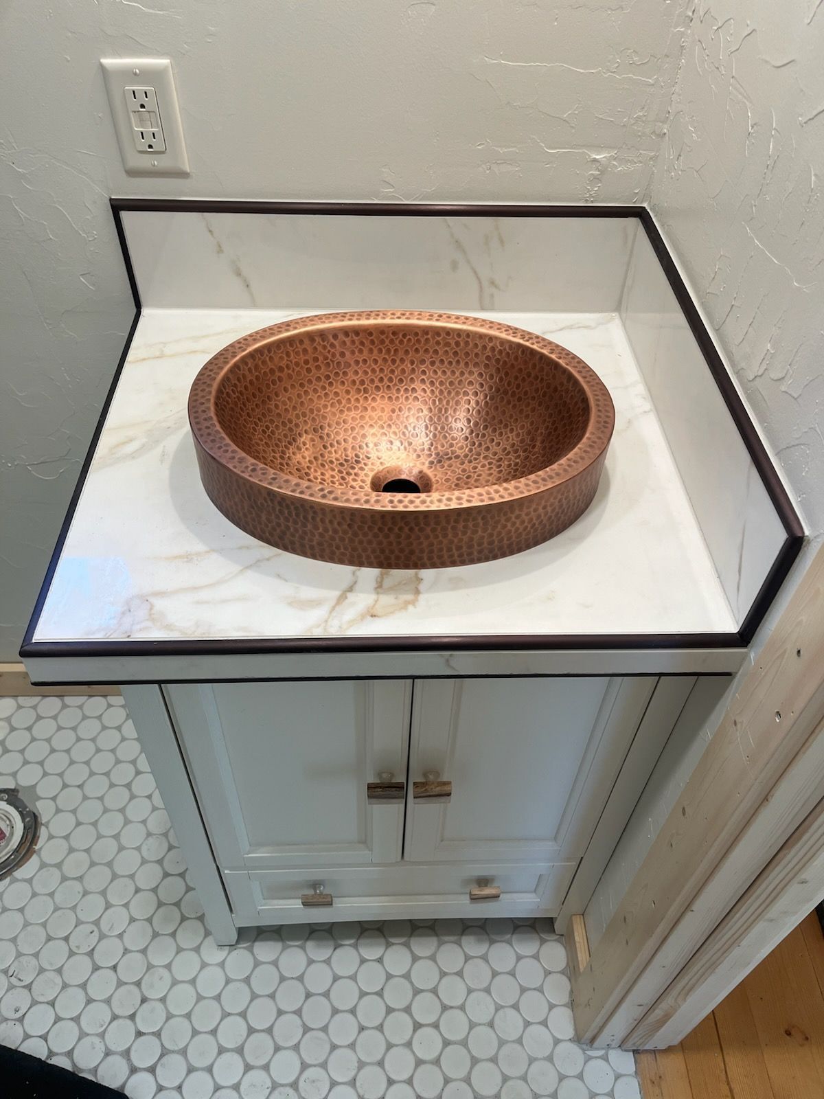A bathroom vanity with a copper sink on top of it.
