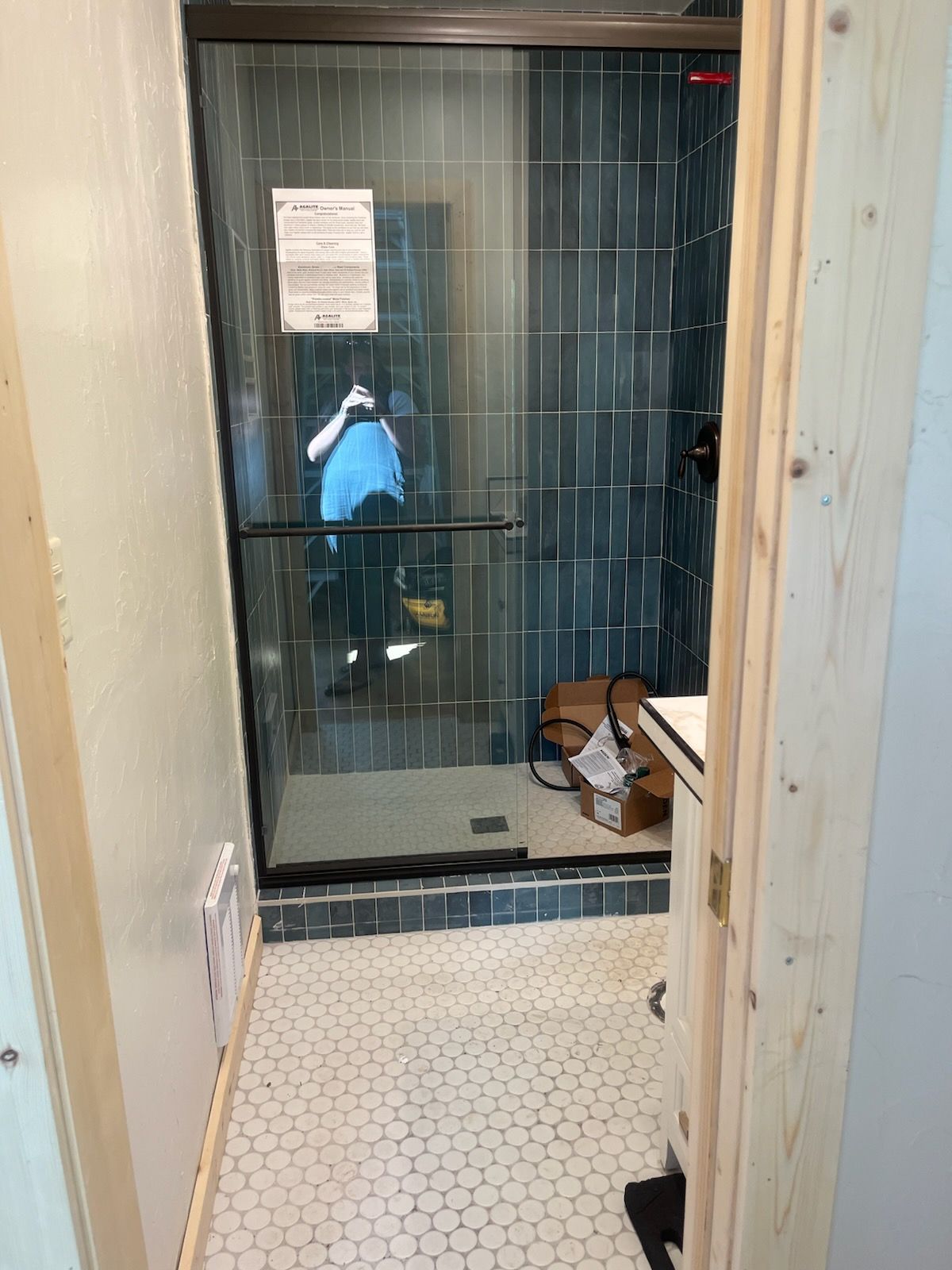A bathroom with a sliding glass shower door and blue tiles.
