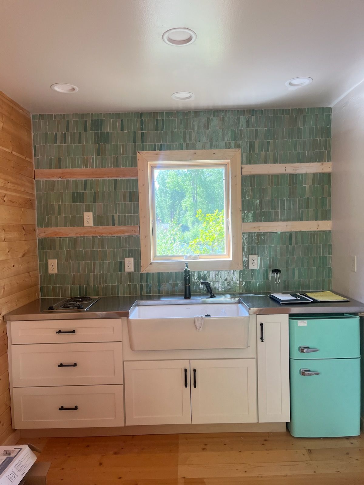 A kitchen with a sink , refrigerator , and window.