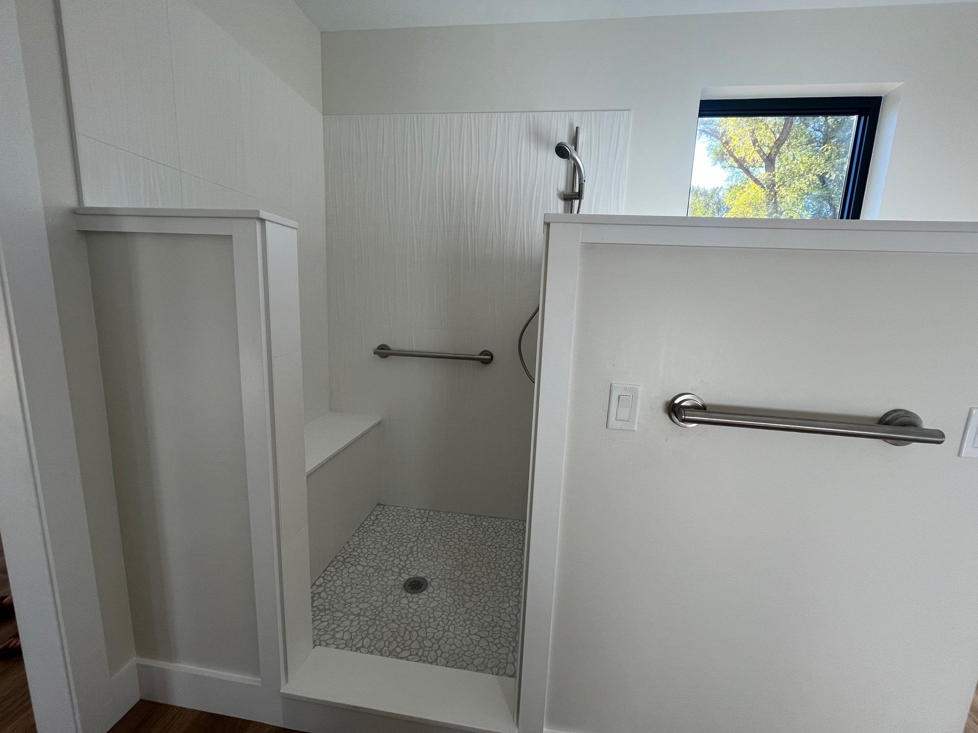 A bathroom with a walk in shower and a window.