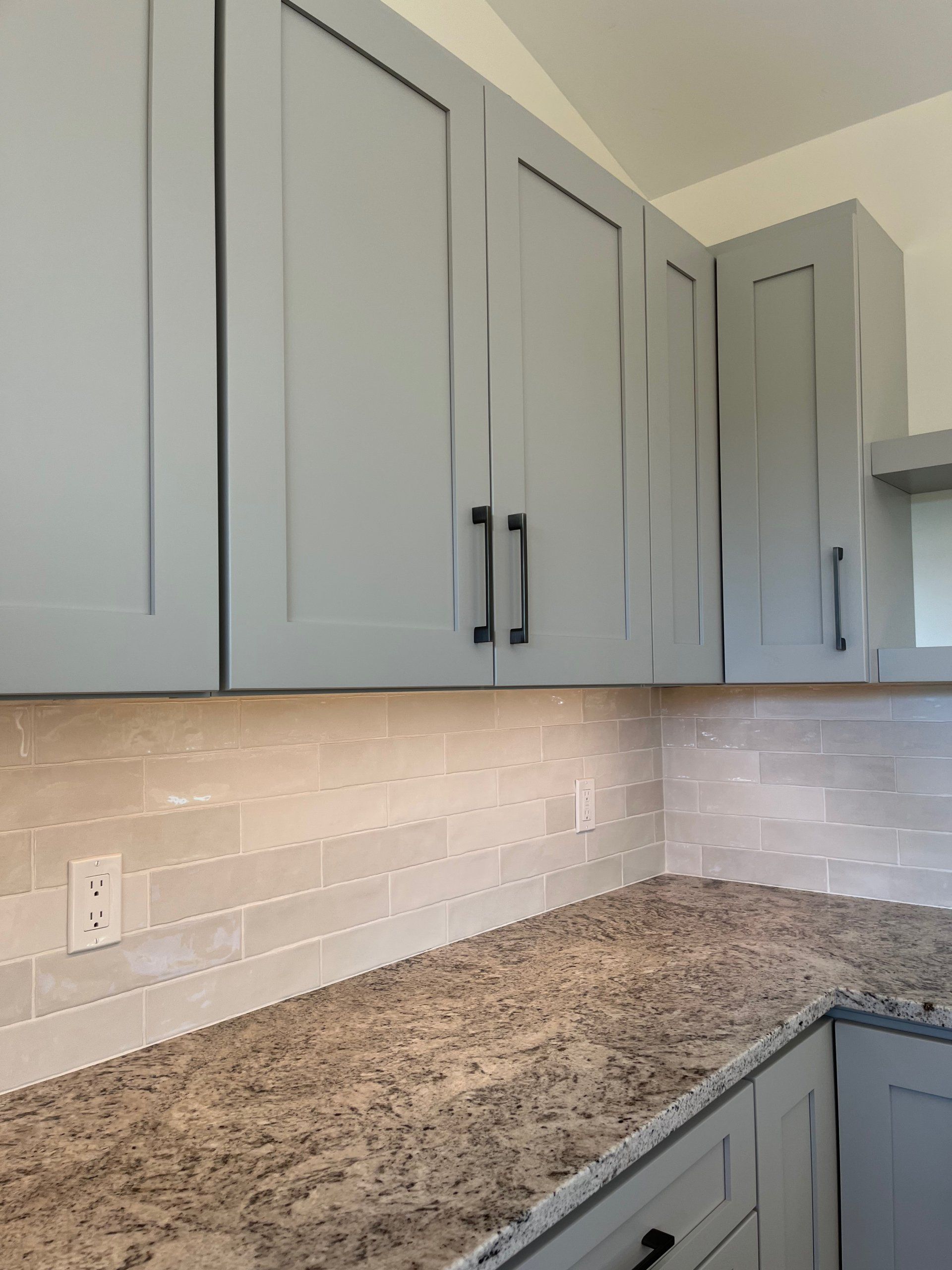 A kitchen with granite counter tops and gray cabinets