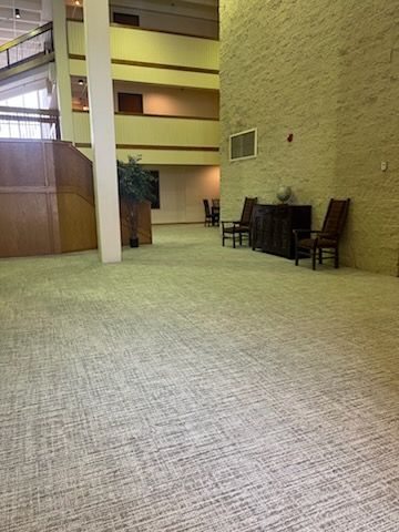 A large empty lobby with a carpeted floor and chairs.