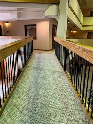 A hallway with a railing and stairs in a building.