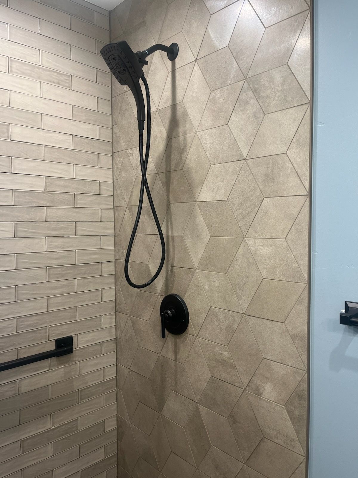 A shower head is hanging from a tiled wall in a bathroom.