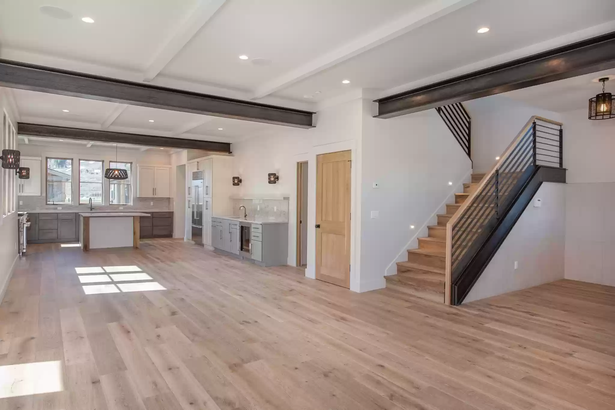 A large empty room with hardwood floors and stairs leading up to the second floor.