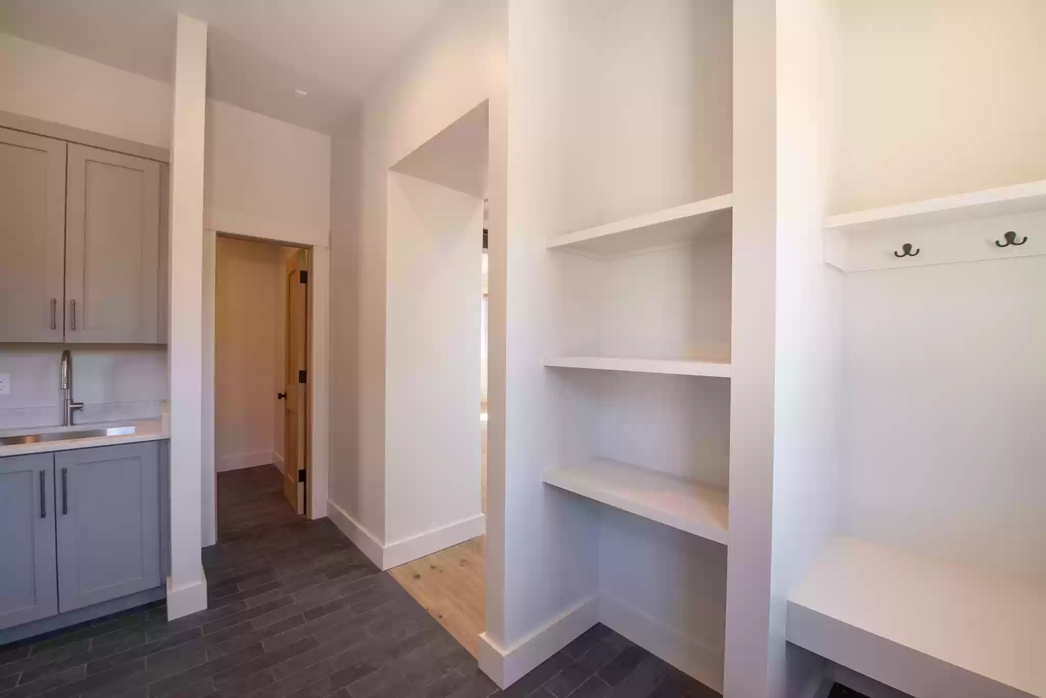 A hallway with a sink and shelves in a house.