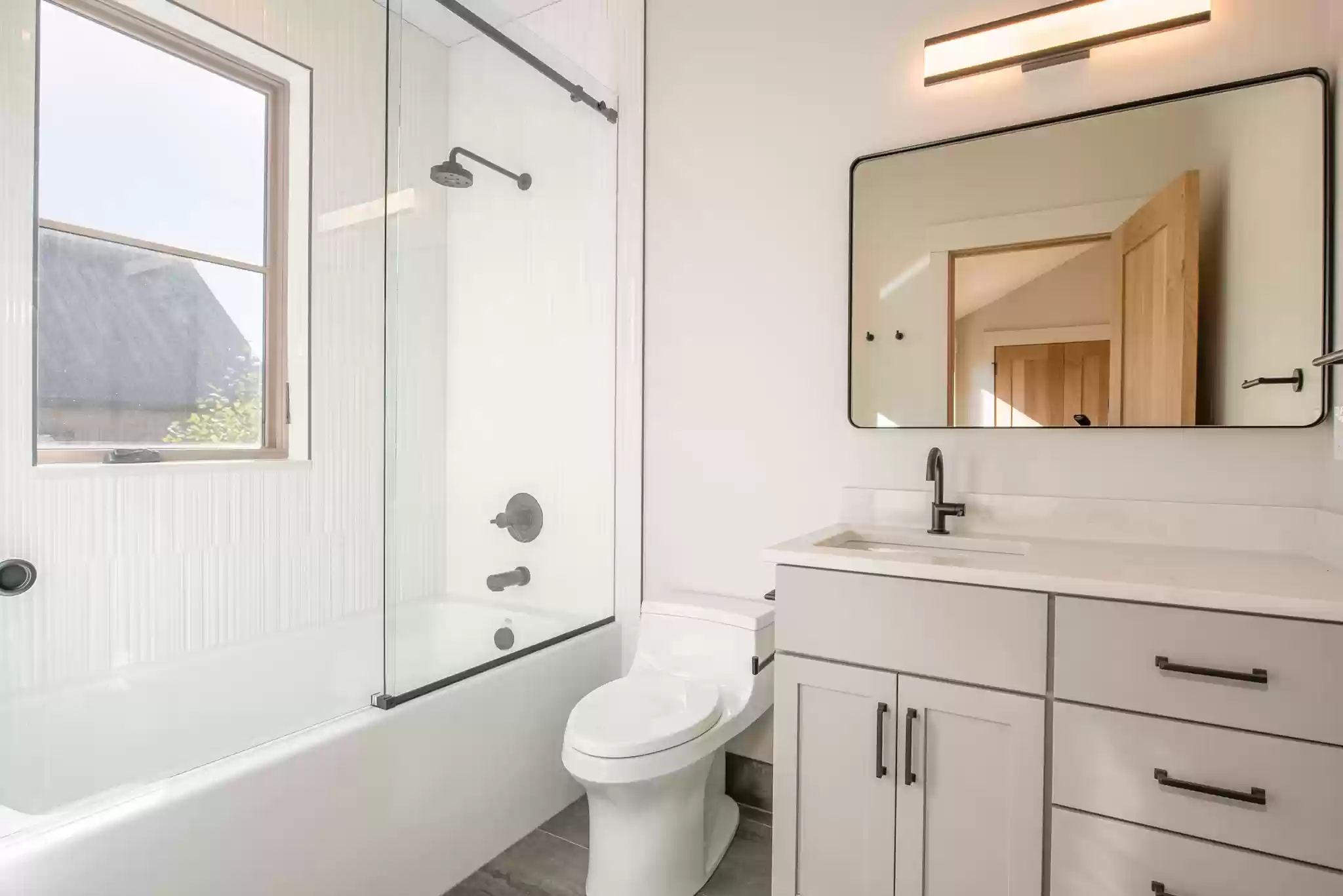 A bathroom with a toilet , sink , bathtub and mirror.