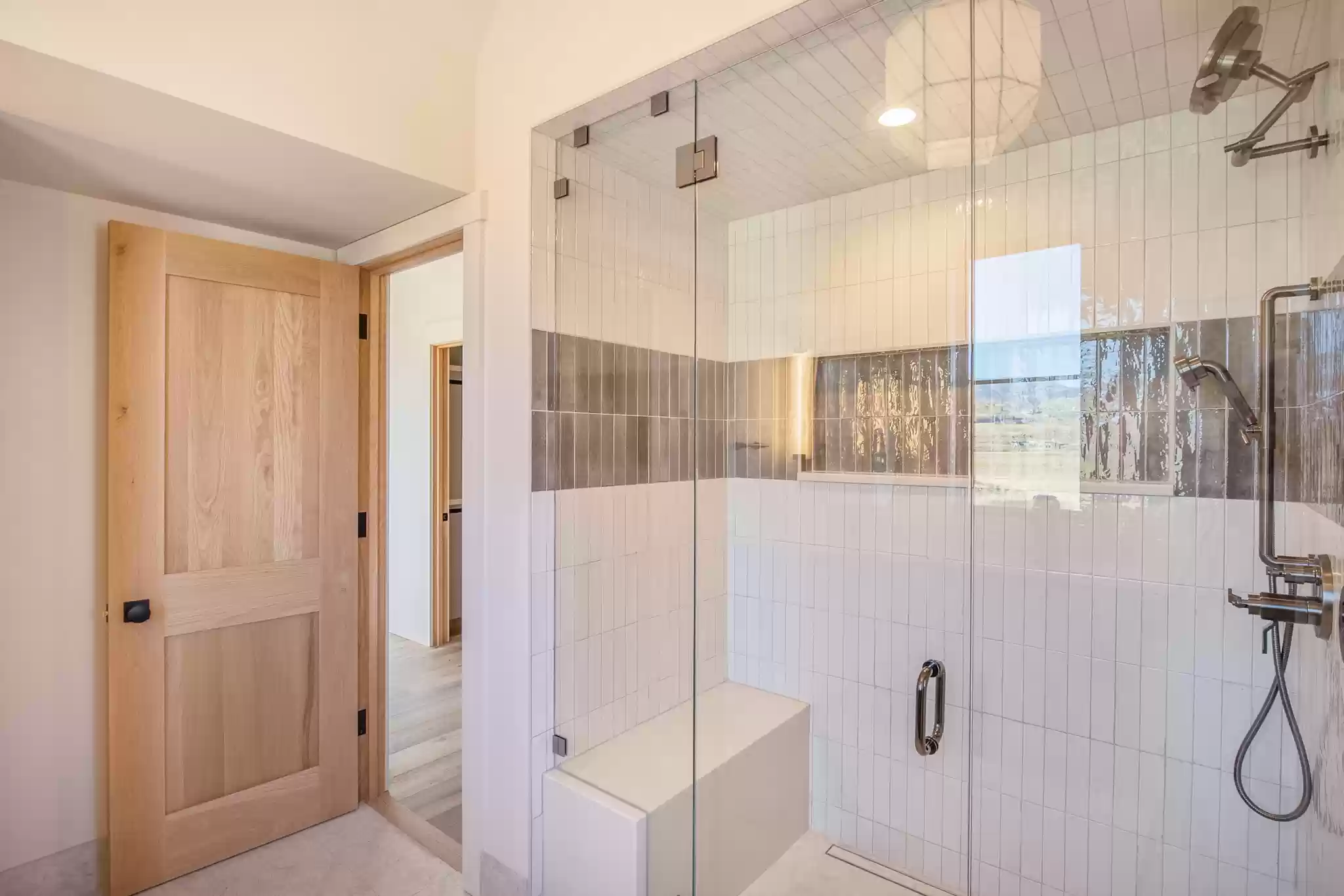 A bathroom with a walk in shower and a wooden door.
