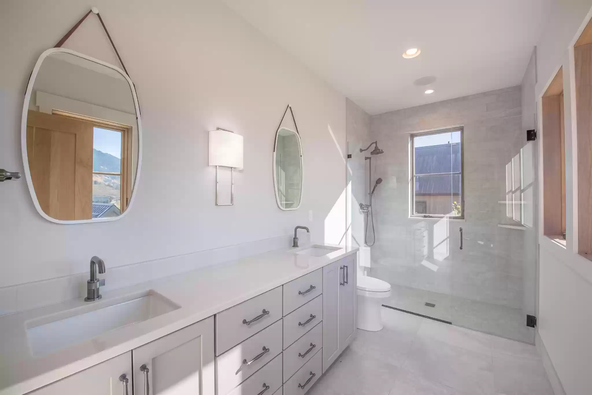 A bathroom with two sinks , a toilet , and a walk in shower.