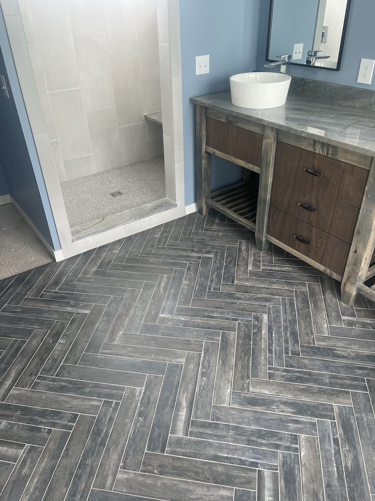 A bathroom with a herringbone floor and a sink.