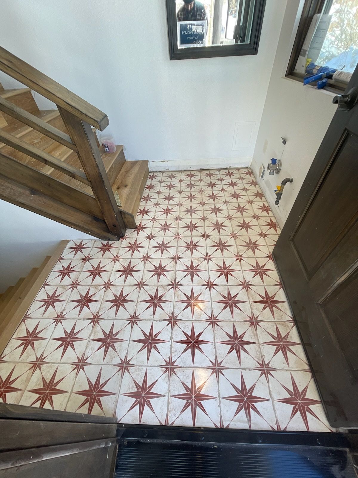 A hallway with stairs and a tiled floor with stars on it.