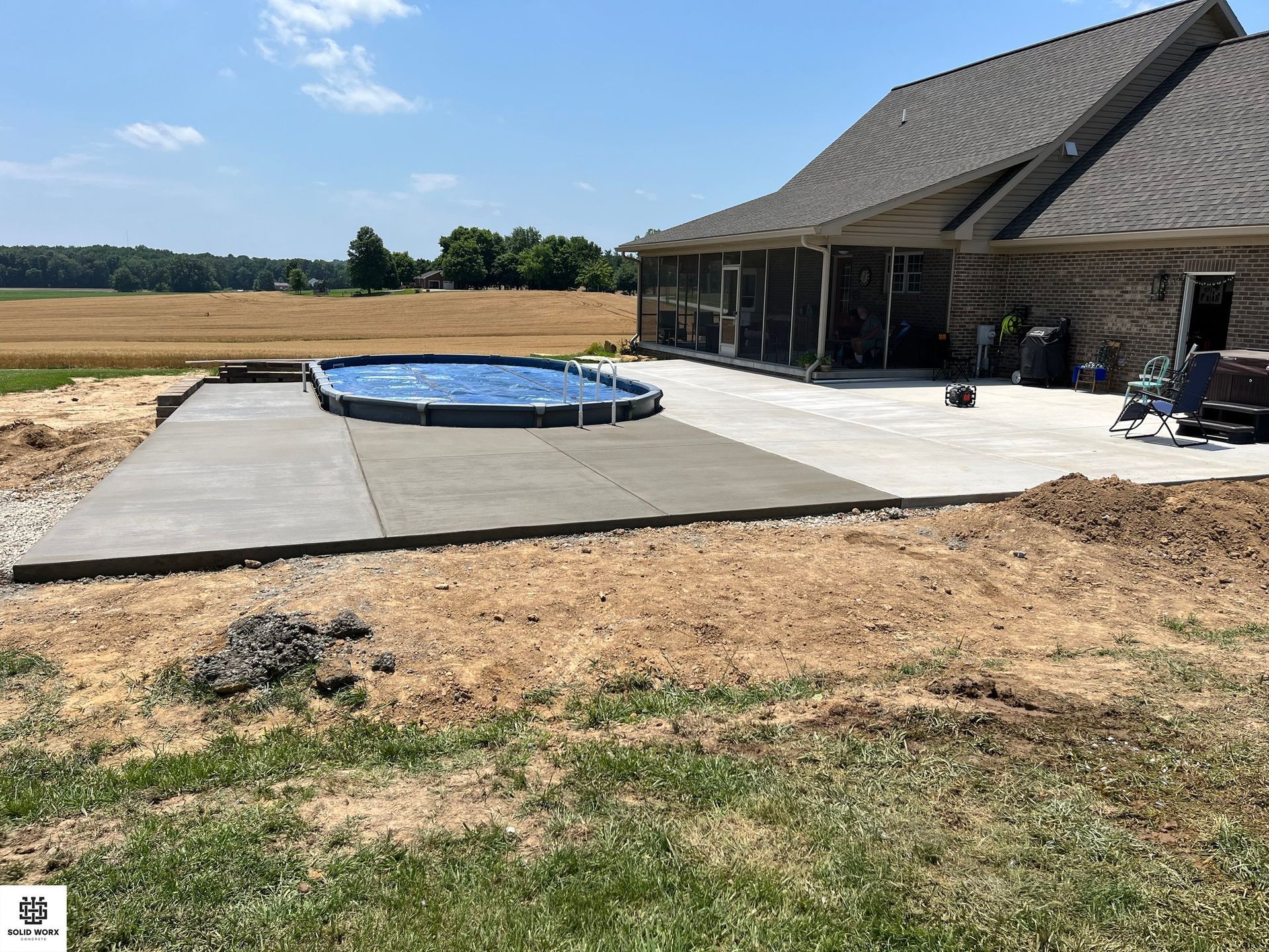 A concrete patio with a pool in the backyard of a house.