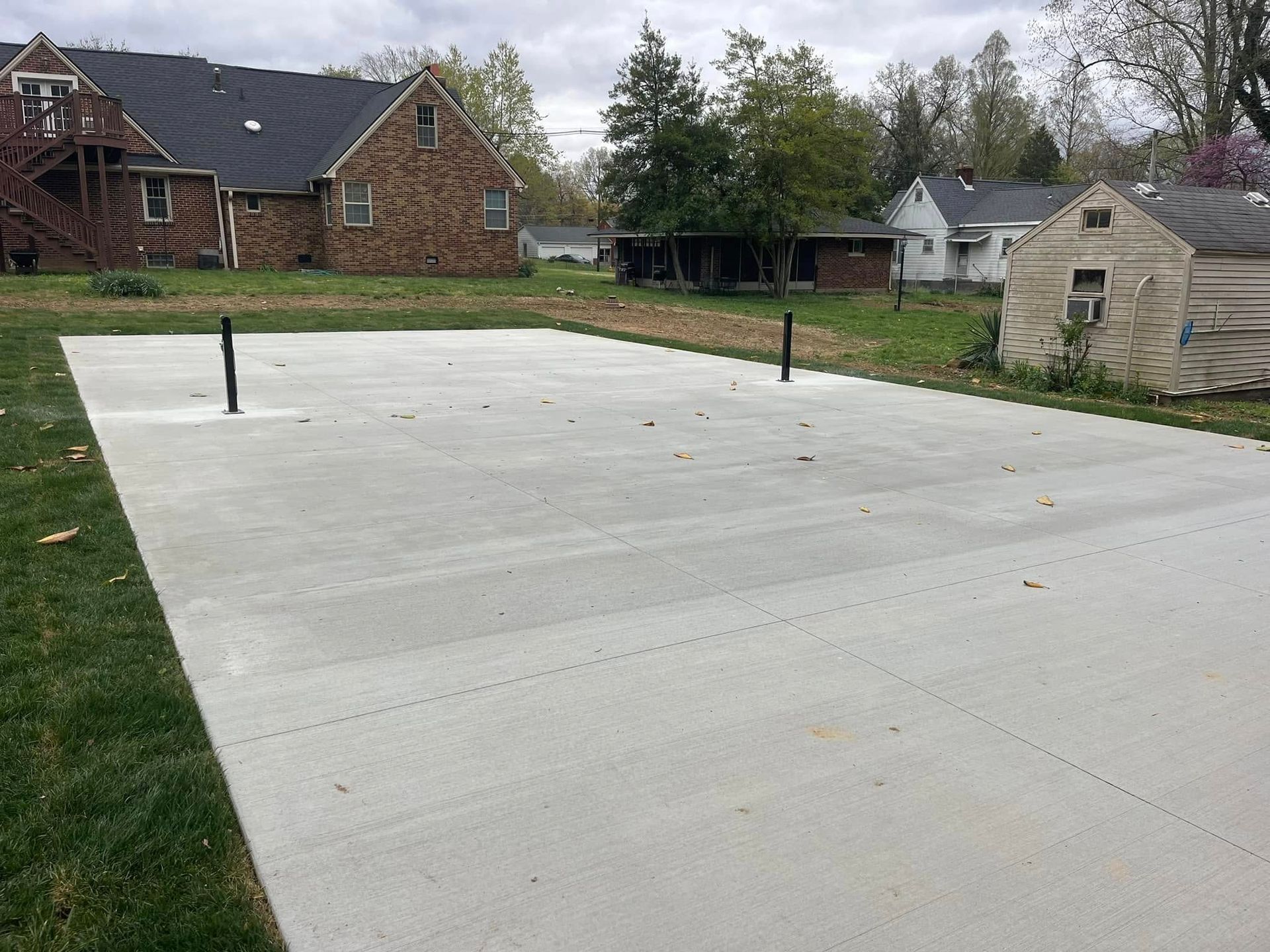 A concrete driveway with a basketball hoop in the middle of it.