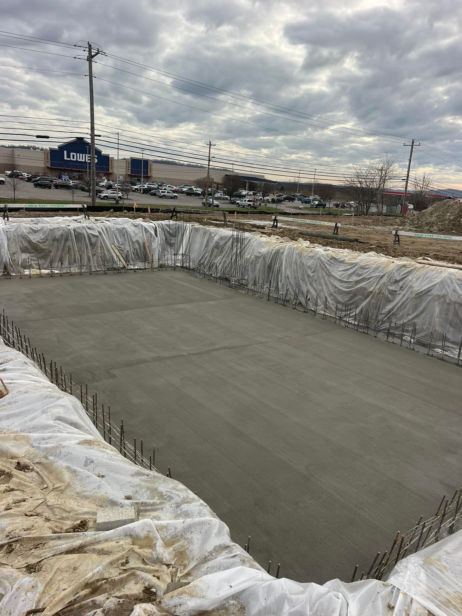 A large concrete pool is being built in front of a large building.
