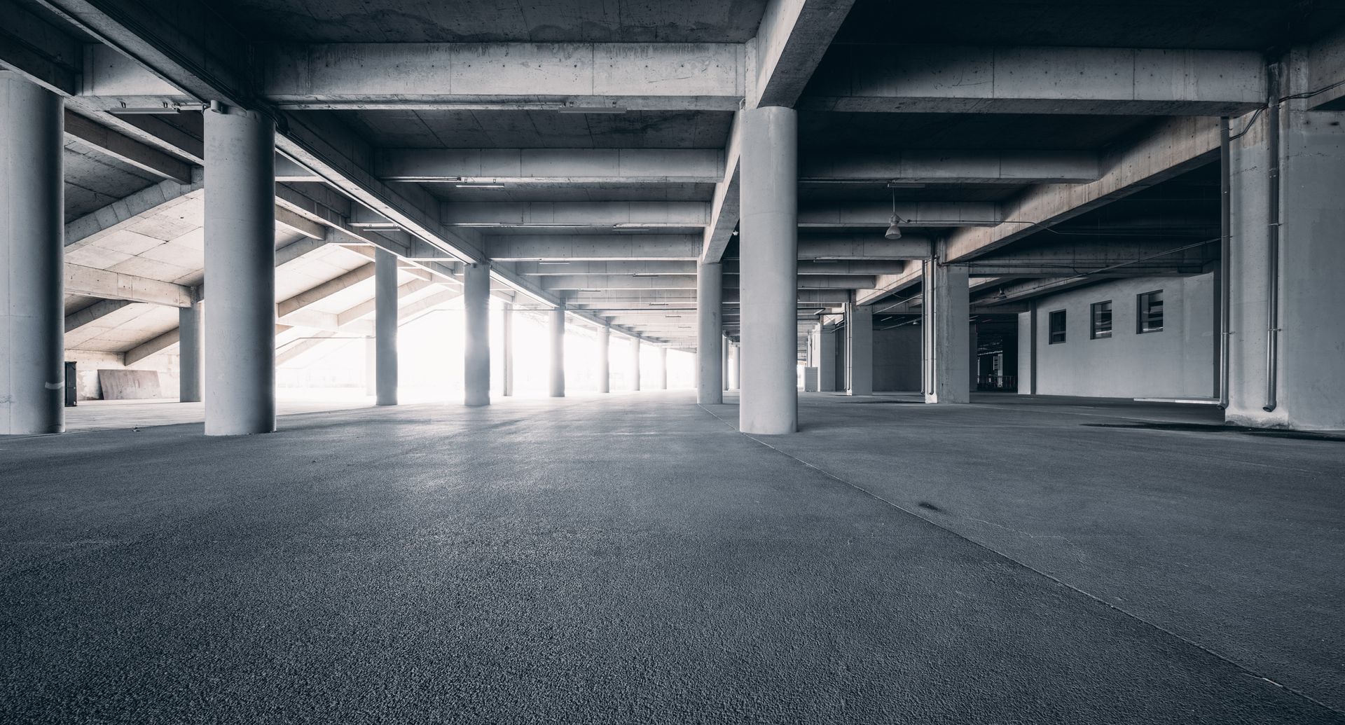 A white semi truck is parked in a warehouse next to a ramp.
