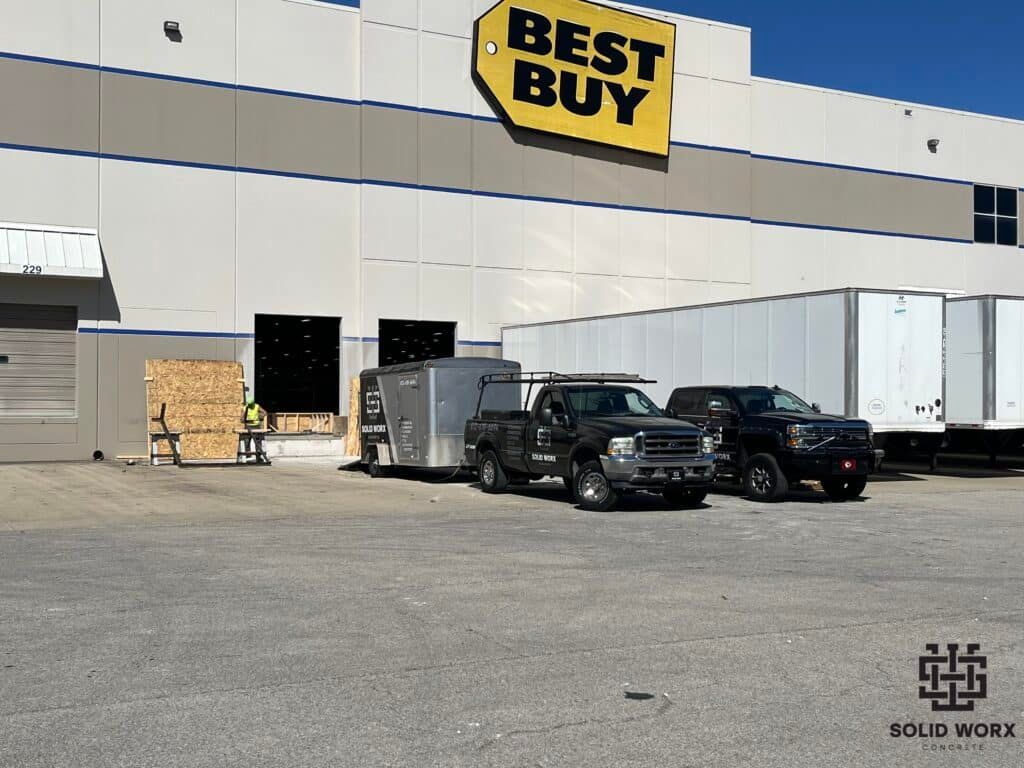 A best buy store with trucks parked in front of it.