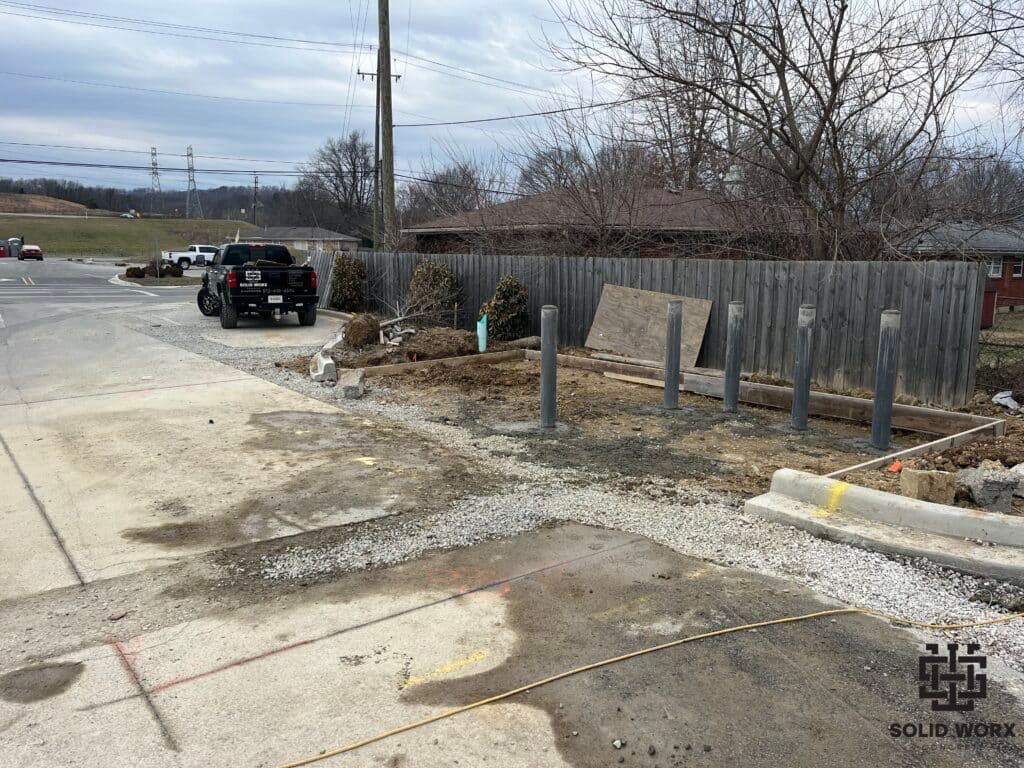 A truck is parked on the side of the road next to a fence.