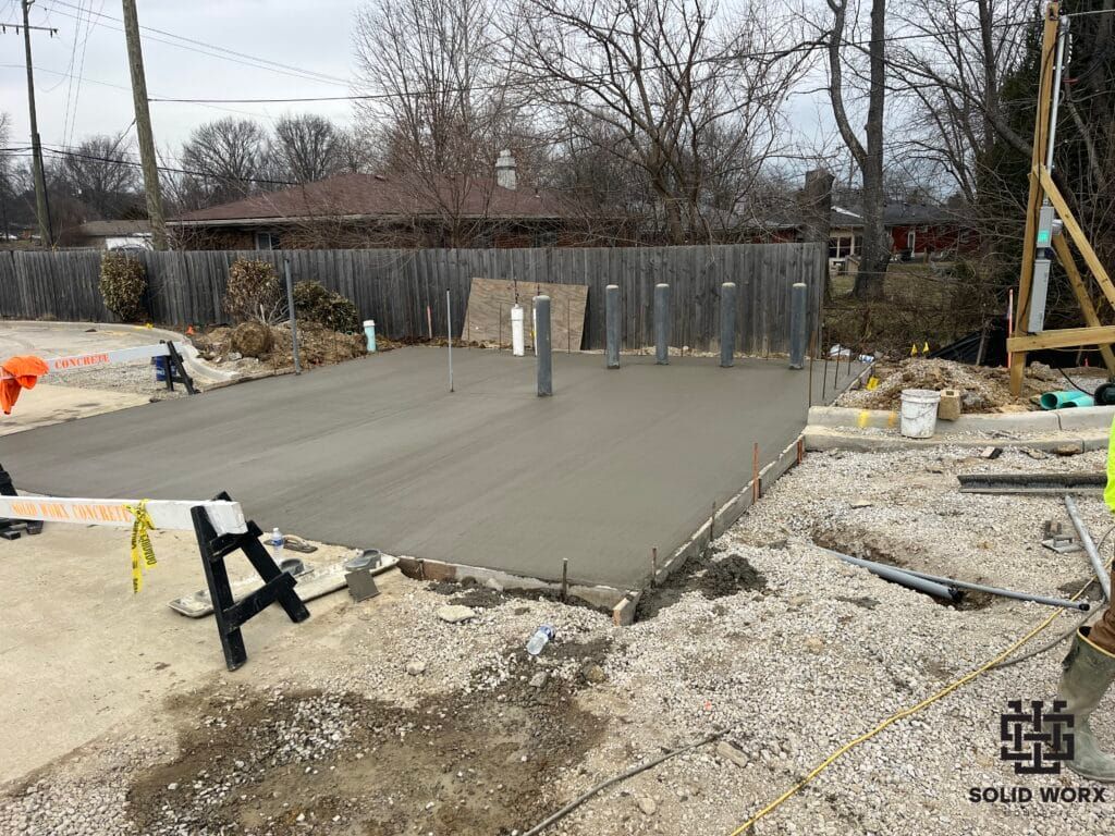 A concrete base is being built in a backyard.