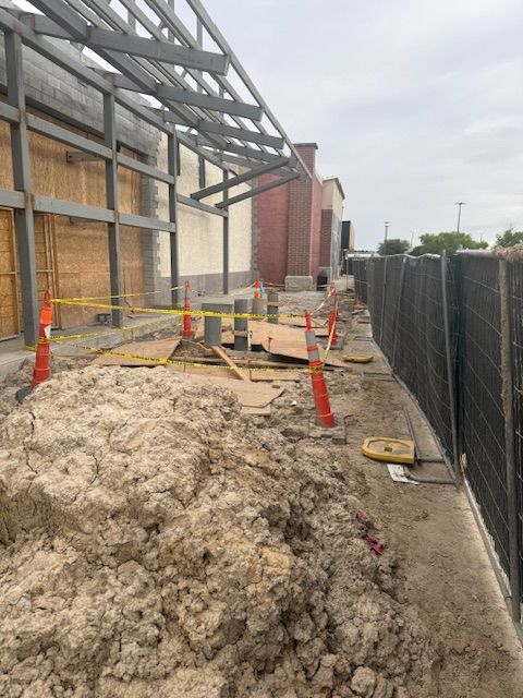 A large pile of dirt is sitting in front of a building under construction.
