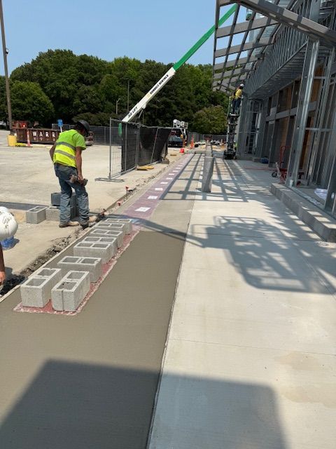 A construction worker is pouring concrete on a sidewalk