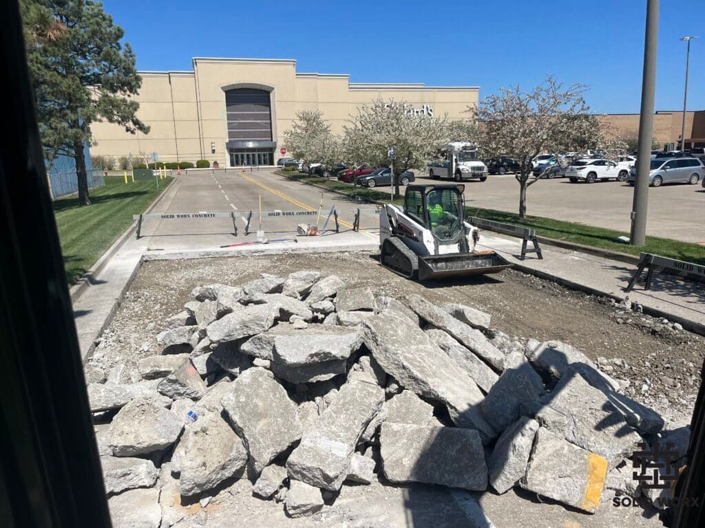 A bulldozer is driving down a road next to a pile of rocks.