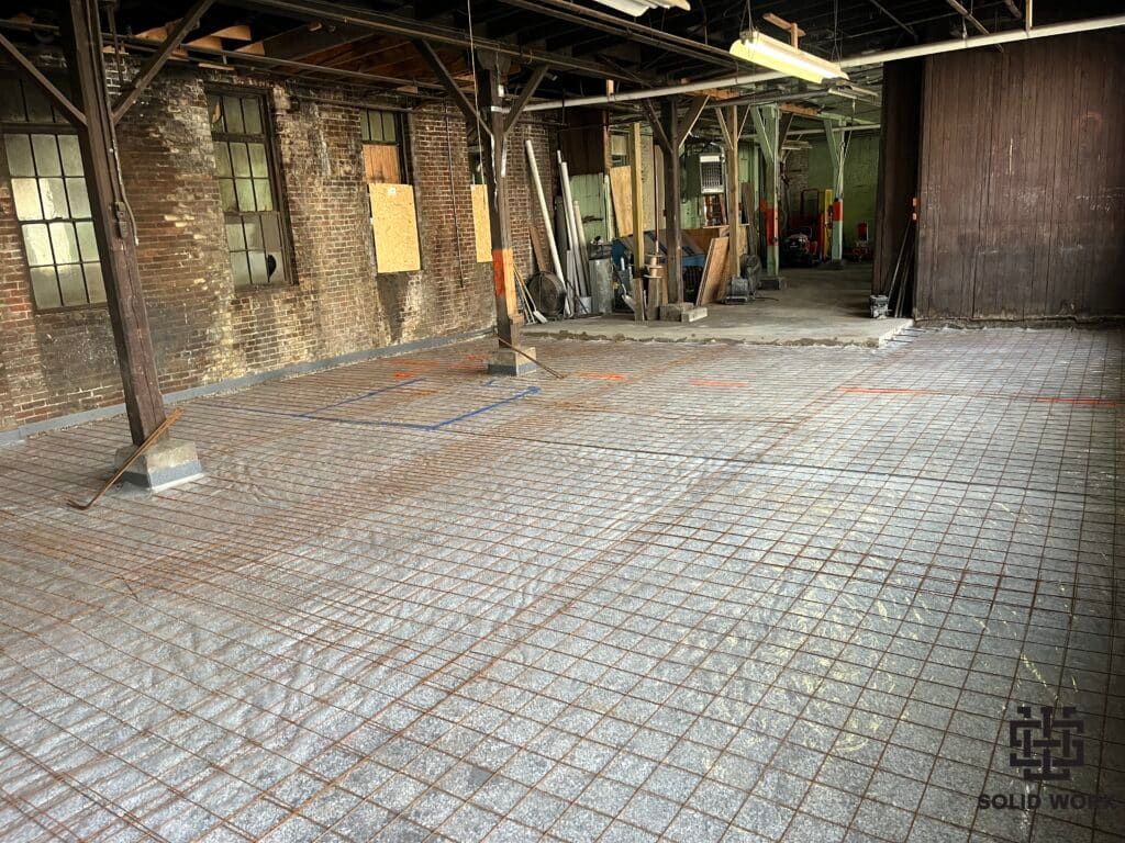 A large empty room with a brick floor and a brick wall.