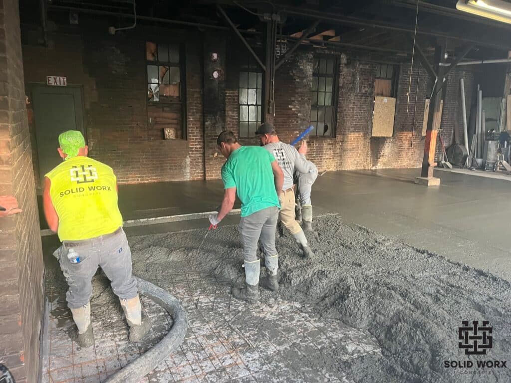 A group of construction workers are working on a concrete floor.