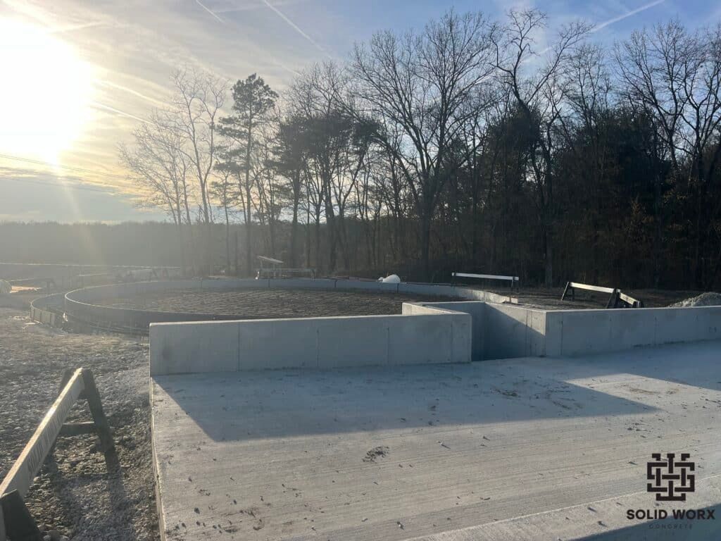 A construction site with trees in the background and the sun shining through the clouds.
