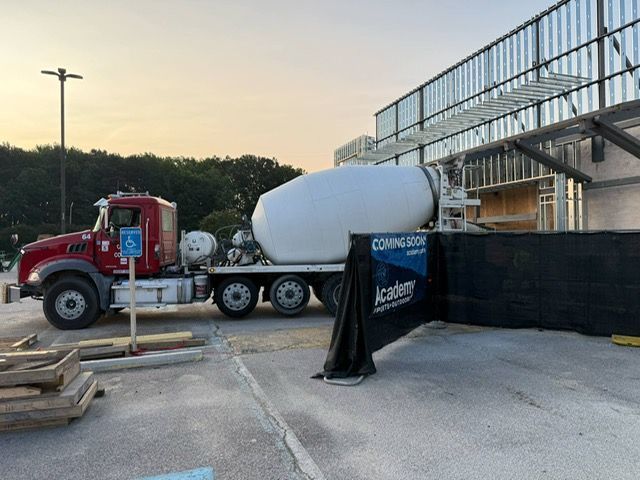A concrete mixer truck is parked in front of a building under construction.