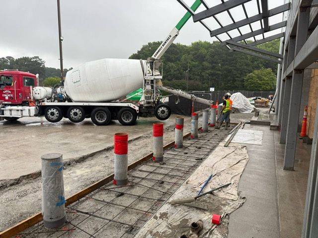 A concrete mixer truck is pouring concrete on a sidewalk.
