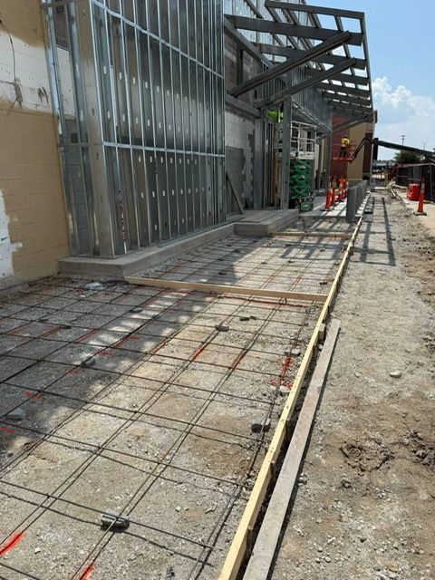 A concrete walkway is being built in front of a building