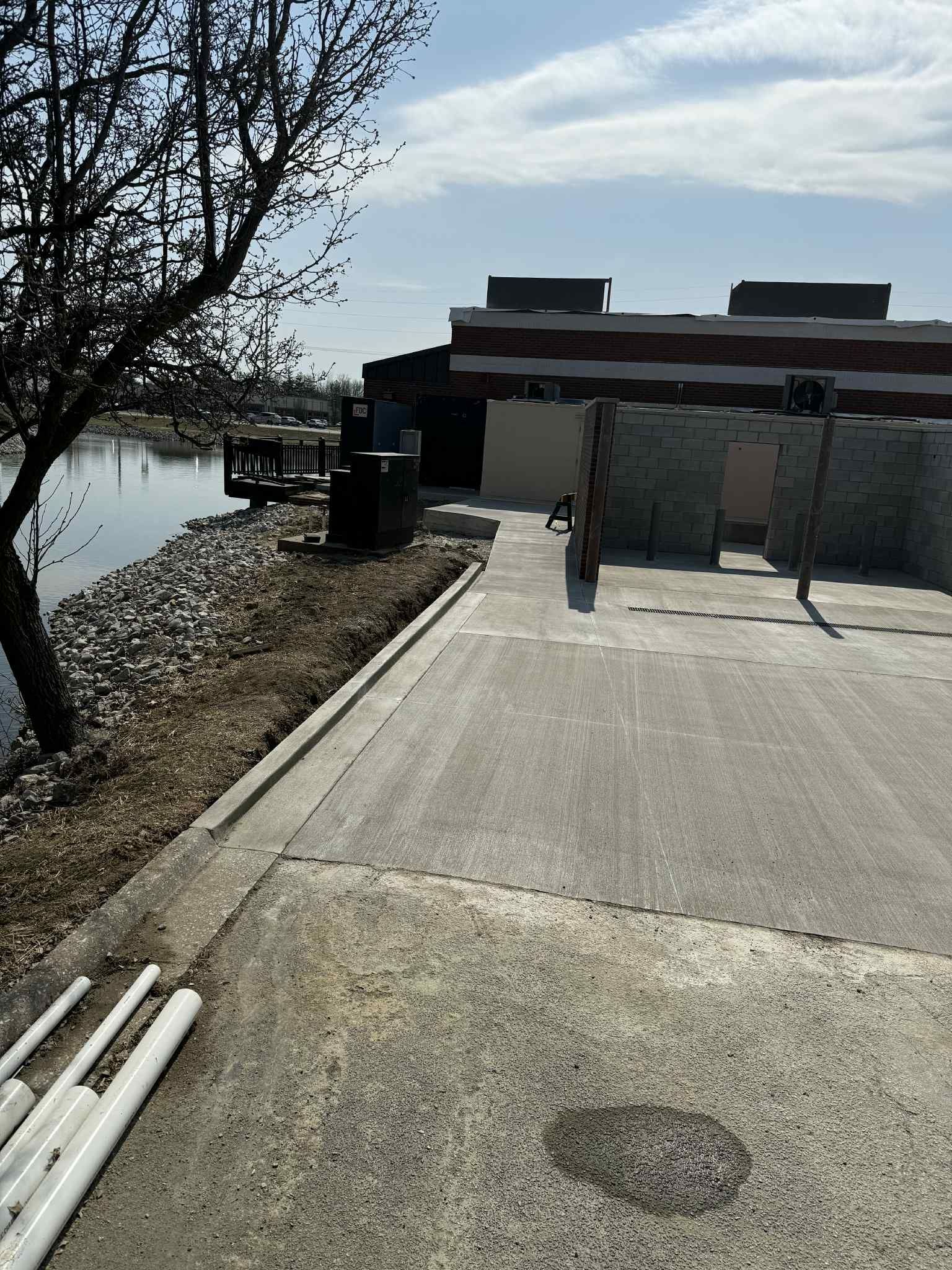 A concrete driveway leading to a building next to a body of water.