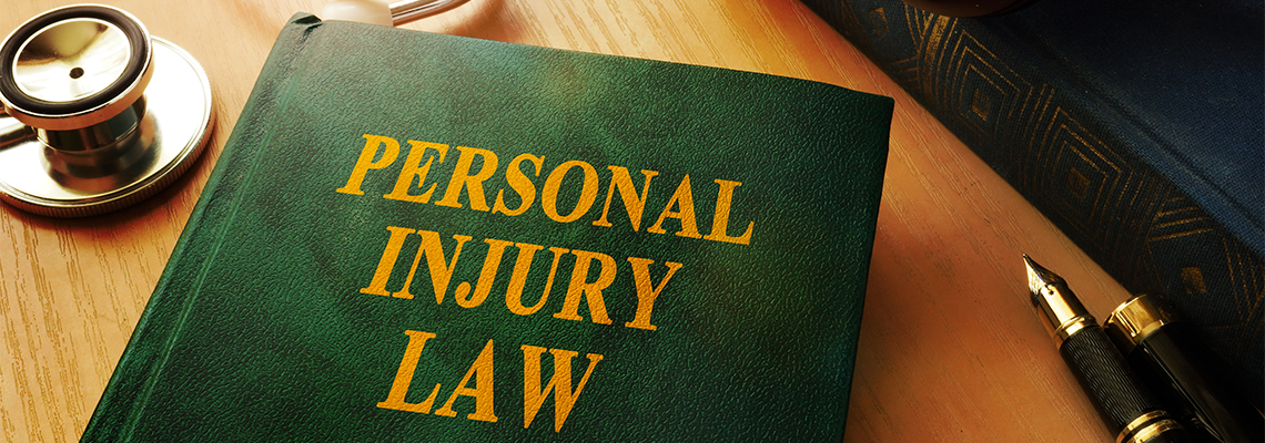 A book titled personal injury law is on a table next to a stethoscope and a pen.
