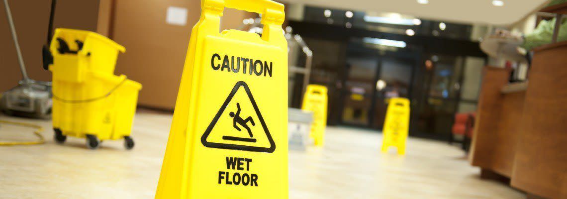 A yellow caution wet floor sign is in a lobby.
