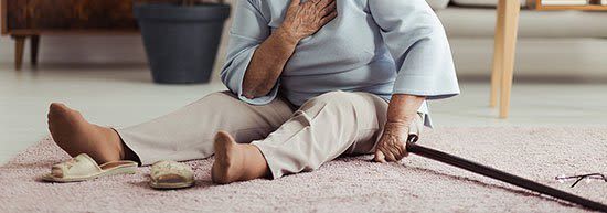 An elderly woman is sitting on the floor with a cane.
