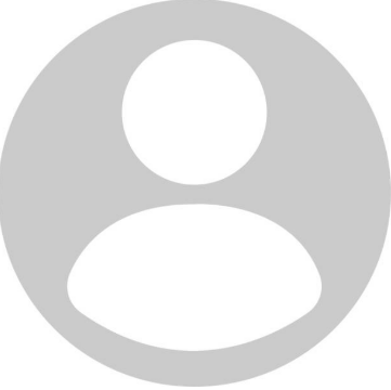 Man with crossed arms on a football field. He is wearing a blue polo shirt, khaki pants, and has a serious expression.