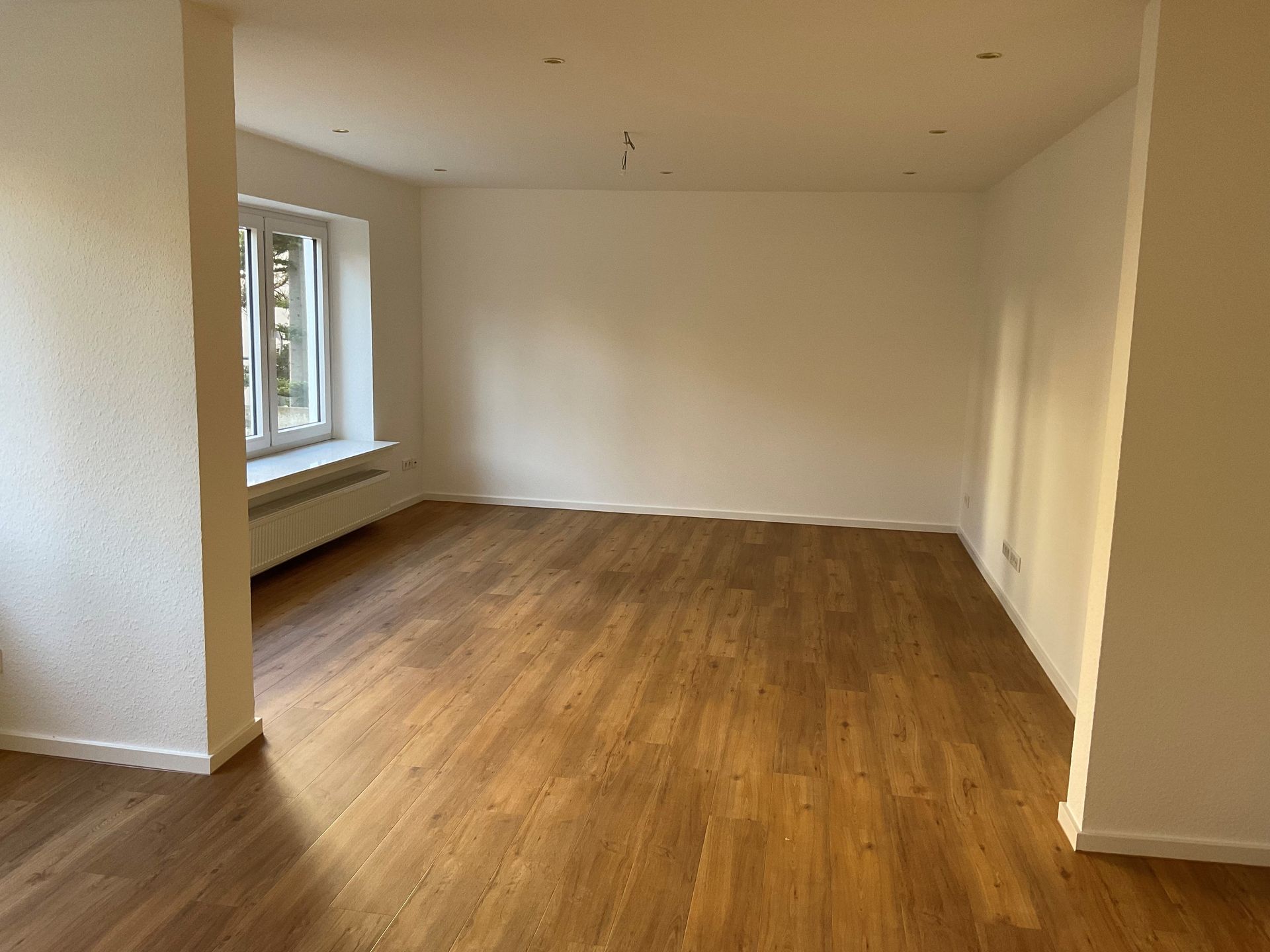 Ein leeres Wohnzimmer mit Hartholzböden und weißen Wänden