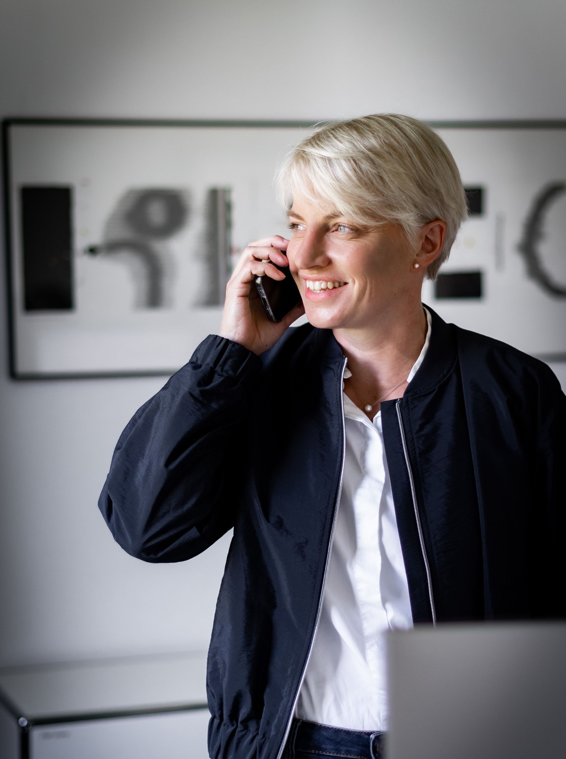 Eine Frau in einer schwarzen Jacke telefoniert mit einem Mobiltelefon