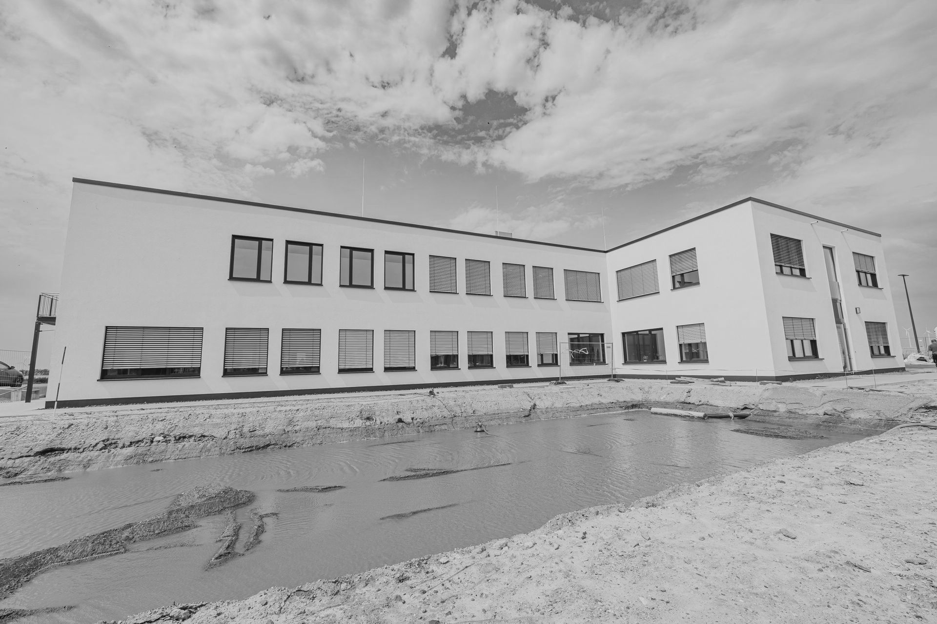 Ein Schwarzweißfoto eines großen weißen Gebäudes mit einem Teich davor.