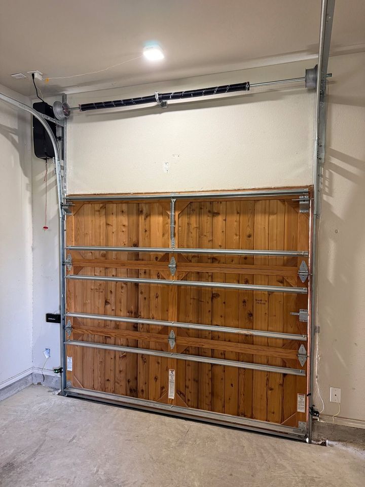 Wooden garage door under construction, with metal framing and unfinished interior wall.