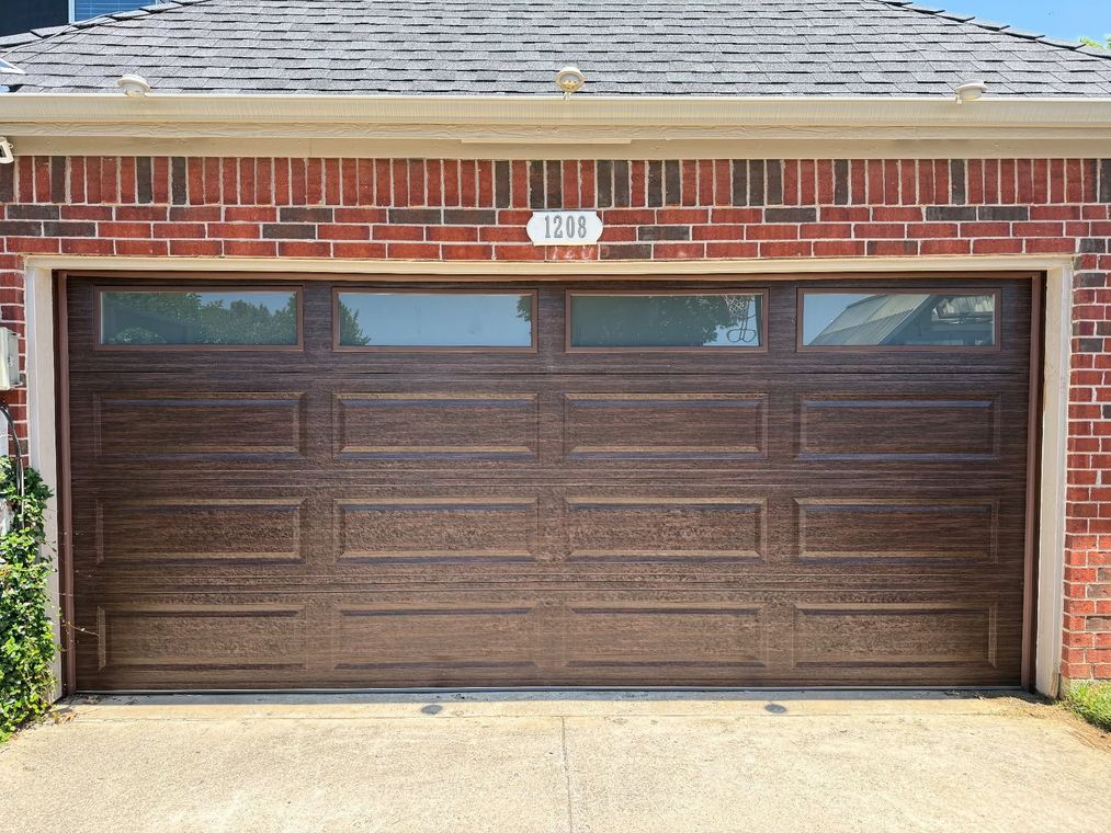 Brown double garage door with four small windows on a brick house exterior